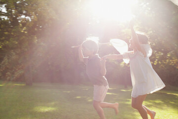 Boy and girl holding hands and running with butterfly nets in grass