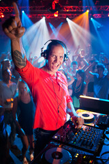 Portrait of enthusiastic DJ at turntable in nightclub