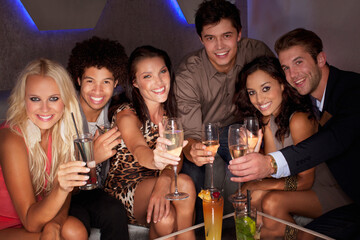 Obraz premium Portrait of smiling friends toasting cocktails in nightclub