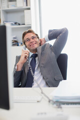 Smiling businessman talking on telephone at desk in office