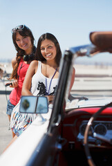 Smiling women standing by convertible
