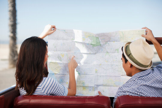 Couple reading road map in convertible