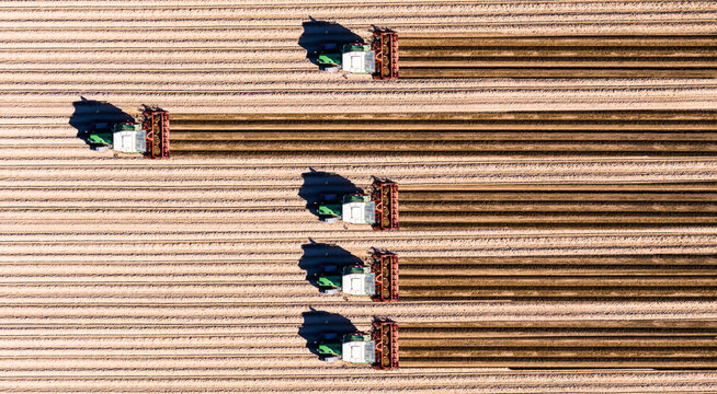 Germany, Hesse, Bergstarsse, Aerial view of tractors plowing brown field in spring