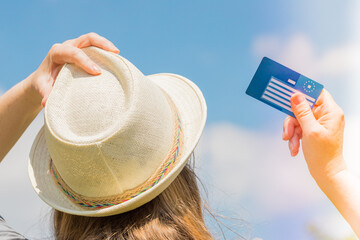 girl in a summer hat holds a European health insurance card against the sky.  Concept, Travel...