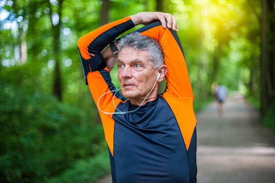 Retired senior man stretching his arms while looking away at park