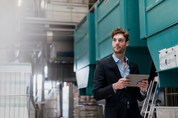 Young businessman holding tablet in a factory