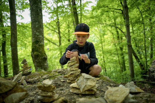 Boy stacking stones as cairn in Swabian Jura forest