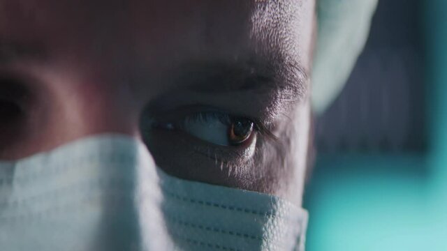 A male scientist or a doctor wearing mask and analyzing neuron, what we see in his eye reflection.