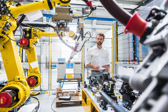 Confident robotics expert looking at machinery in manufacturing factory