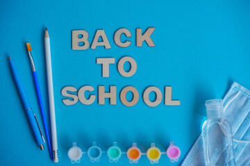 Study flatlay concept. Education supplies-pencil,pen,brush, paint, medical mask and sanitizer paint on blue background,back to school or kindergarten. summertime, creativity and learn background with