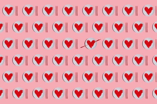 Pattern of plates with red-colored heart-shaped spaghetti against pink background