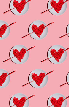 Pattern of plates with red-colored heart-shaped spaghetti against pink background