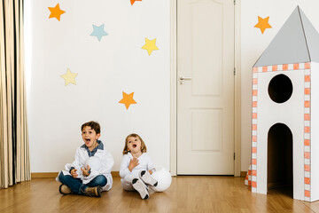 Siblings playing astronaut and researcher at rocket
