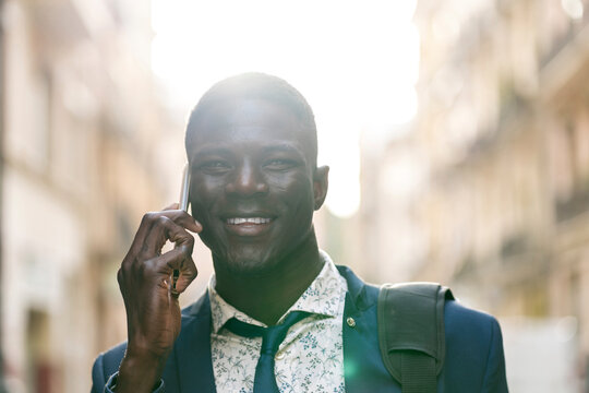 Portrait of smiling young businessman on the phone at backlight
