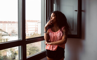 Young woman smoking a cigarette at the window