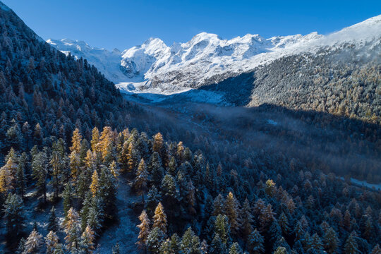 Switzerland, Canton of Grisons, Saint Moritz, Drone view of fog floating over forested valley of Morteratsch Glacier in autumn