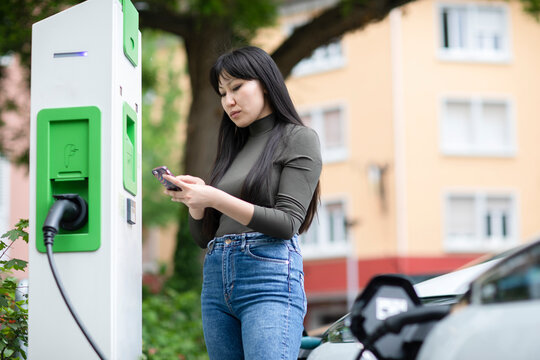 Carsharing, woman renting an electric car using smartphone