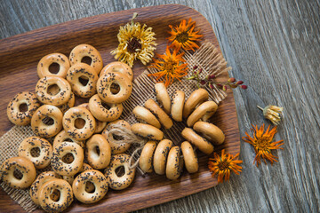 bagels with poppy seeds lie on a tray decorated with flowers