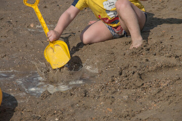 
little kid playing in the sandbox with a toy shovel
