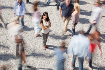 Portrait of confident woman standing among rushing crowd