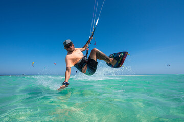 kiter does a difficult trick on a background of transparent water and blue sky