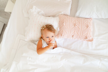 Fototapeta na wymiar little girl sleeping in bed in bedroom with crown. Princess birthday party. 