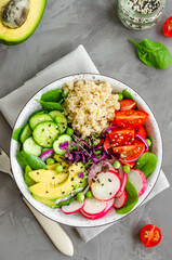 Quinoa salad with fresh vegetables, spinach, green peas, microgreens and sesame seeds in a bowl in a concrete background. Healthy food concept. Vertical orientation. Top view.