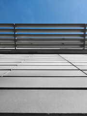 Grey tiles clad building with a metal shade panel on a blue sky