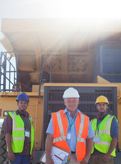 Businessman and workers by machinery on site