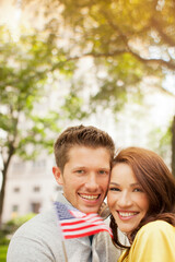 Fototapeta premium Couple waving American flag in urban park