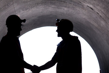 Silhouette of workers shaking hands in tunnel