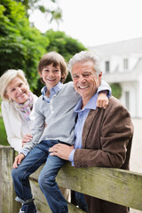 Couple and grandson smiling by wooden fence