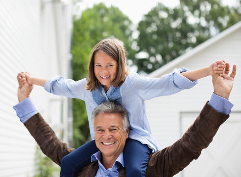 Man Carrying Granddaughter On Shoulders