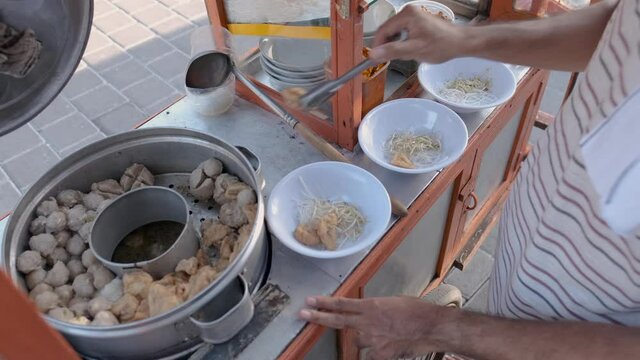 bakso. indonesian famous meatball street food vendor close up hand serving