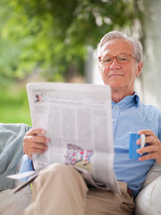 Man reading newspaper in porch swing