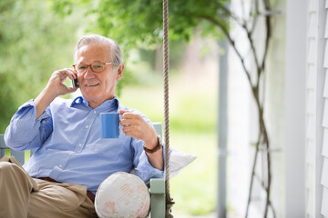 Man talking on cell phone in porch swing - Powered by Adobe
