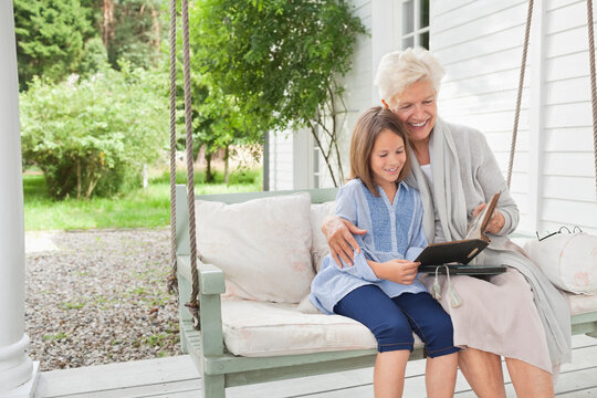 Woman and granddaughter reading on porch swing