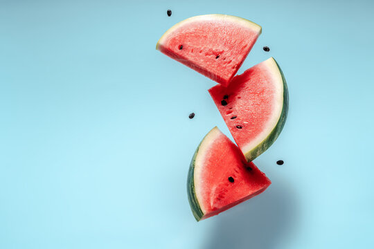 Watermelon slice falling on pastel background. Floating fruits in the air. Flying red fruits. Summer background. Trend colors, copy space.