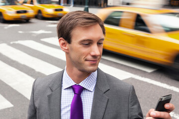 Businessman using cell phone on city street