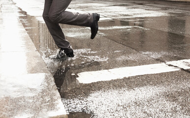 Businessman stepping in puddle on city street