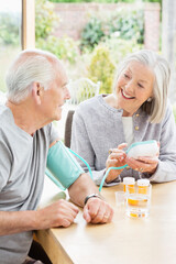 Older woman testing husband's blood pressure