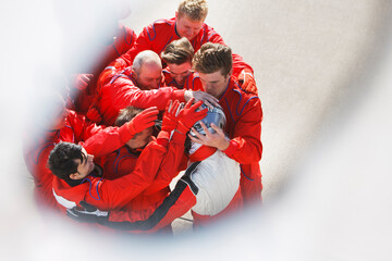 Racing team hugging racer at pit stop