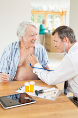 Obraz premium Doctor listening to older patient's heartbeat at house call
