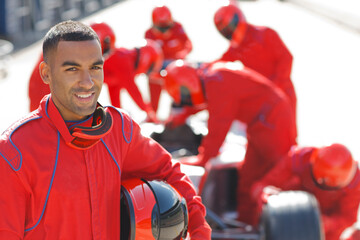 Racer standing with team in pit stop