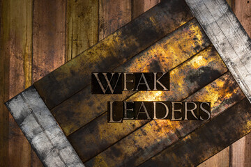 Photo of real authentic typeset letters forming text Weak Leaders on vintage textured silver grunge...