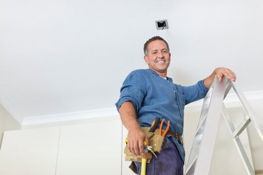 Man working on ceiling lights - Powered by Adobe