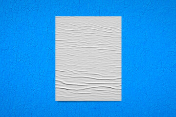 White crumpled sheet of paper on a blue background.