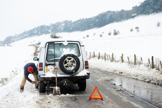 Man Working On Broken Down Car In Snow