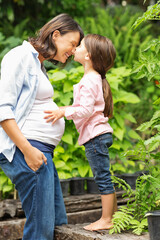 Naklejka na ściany i meble Girl kissing pregnant mother outdoors