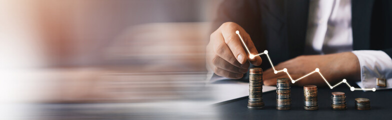Businessman stacking coins with a graph of profit. Panoramic banner with copy space.
